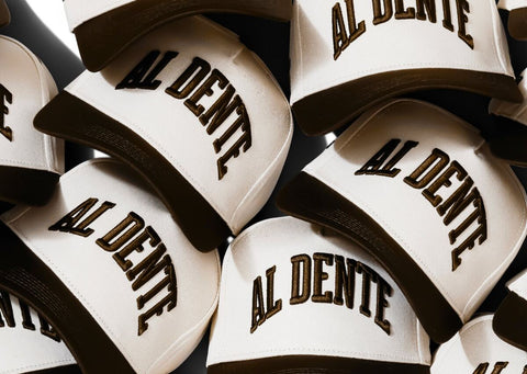 A pile of Al Dente Hat II hats in Cream/Espresso